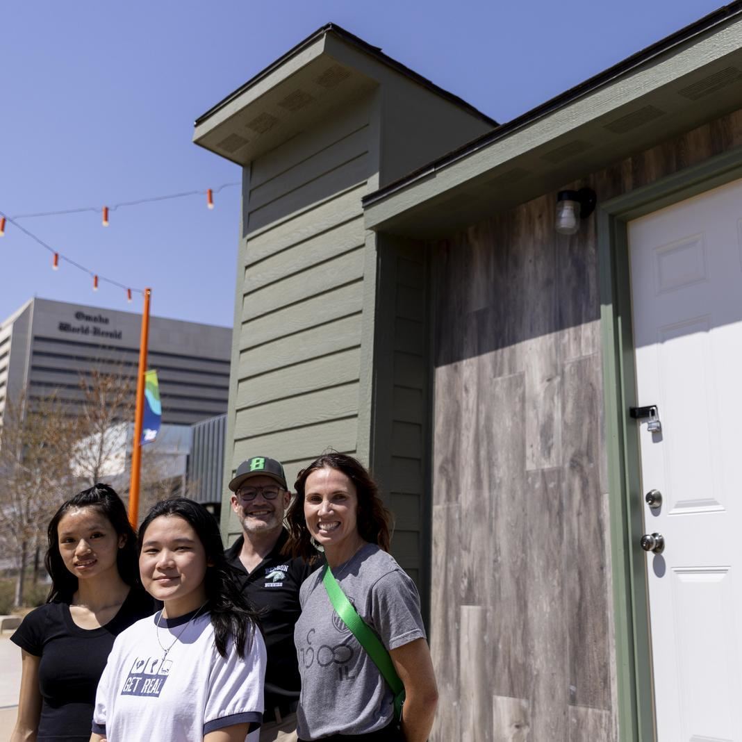  Students and staff stand in front of the tiny house at the riverfront
